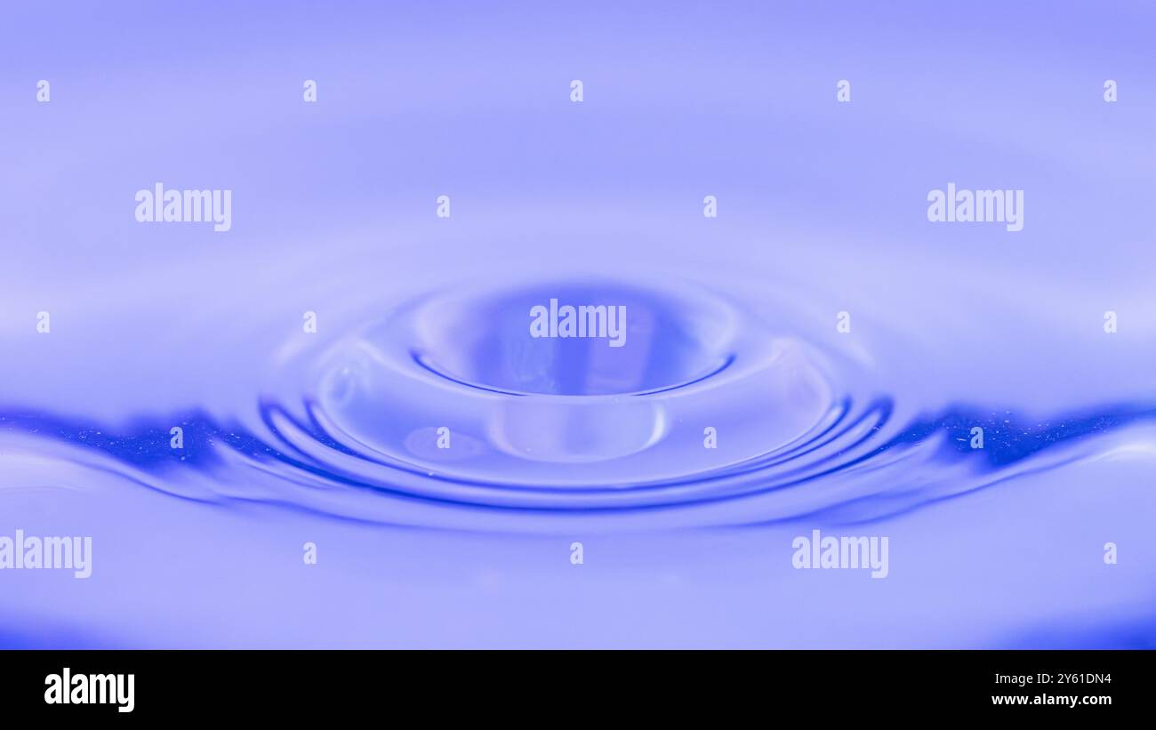 Minimalistische Fotografie, von einem Wassertropfen, einem Spritzer, einer Welle, die sich auf der Wasseroberfläche ausbreitet, Bild, das Ruhe, Meditation, Ruhe anregt Stockfoto
