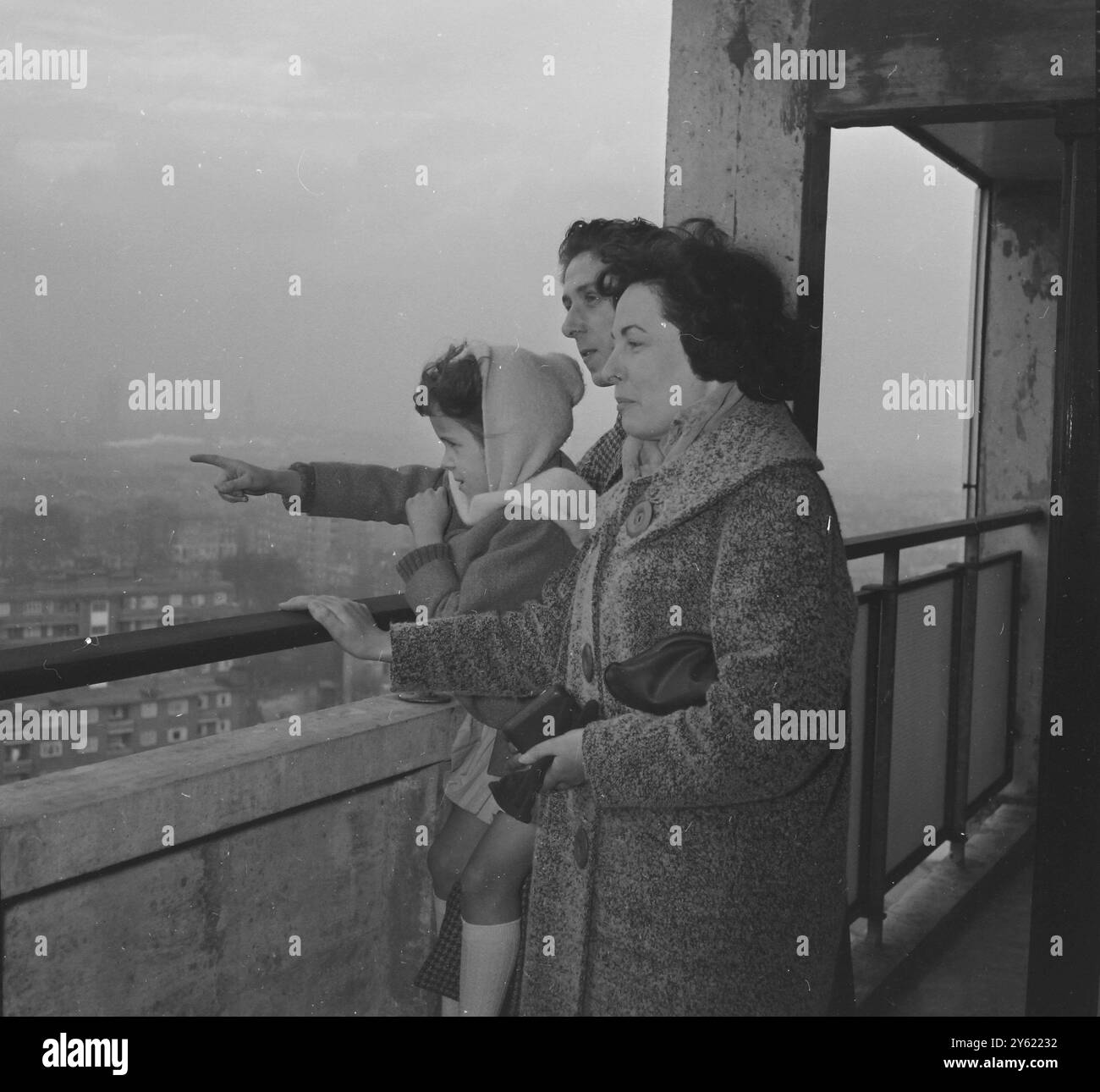 Mr. Und Mrs. O'Brien und ihre 6-jährige Tochter Debra stehen hier im 16. Stock des 18-stöckigen Cornish House im Brandon Estate des LCC und sehen sich die Aussicht an, die sie genießen werden, wenn sie bald einziehen. Bei einer Zeremonie übergab der Bürgermeister von Southwark, George Darvell, den O'Brien den Schlüssel zu ihrer Wohnung im 16. Stock. Cornish House ist einer der 6 18-stöckigen Blöcke, die hier bald fertiggestellt werden und für Mieter bereit sind, und jedes mit 64 3-Schlafzimmer-Wohnungen und Zentralheizung und Aufzügen. Sie sind die höchsten Wohngebäude, die seit dem Krieg fertiggestellt wurden, London, England.19 JANU Stockfoto