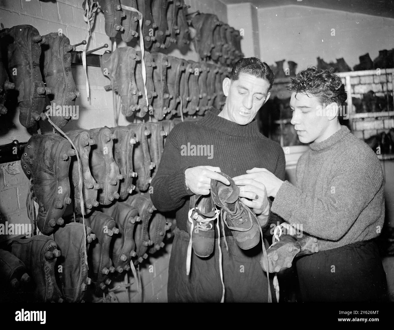 „Battling“ Billy Thompson, britischer Leichtgewichtsmeister von Hickleton Main, absolviert sein Training auf dem Highbury Ground des berühmten Arsenal Football Clubs. Billy trifft am 17. Februar in Haringay auf Roberto Pricetti (Italien), um den Europameistertitel zu gewinnen. Das Bild zeigt: „Ich bevorzuge Handschuhe“. Scharfe Schießerei Ronnie Rooke, Arsenal Mittelstürmer (links) zeigt Billy Thompson seine Schießschuhe am Arsenal Ground, heute. 3. Februar 1948 Stockfoto