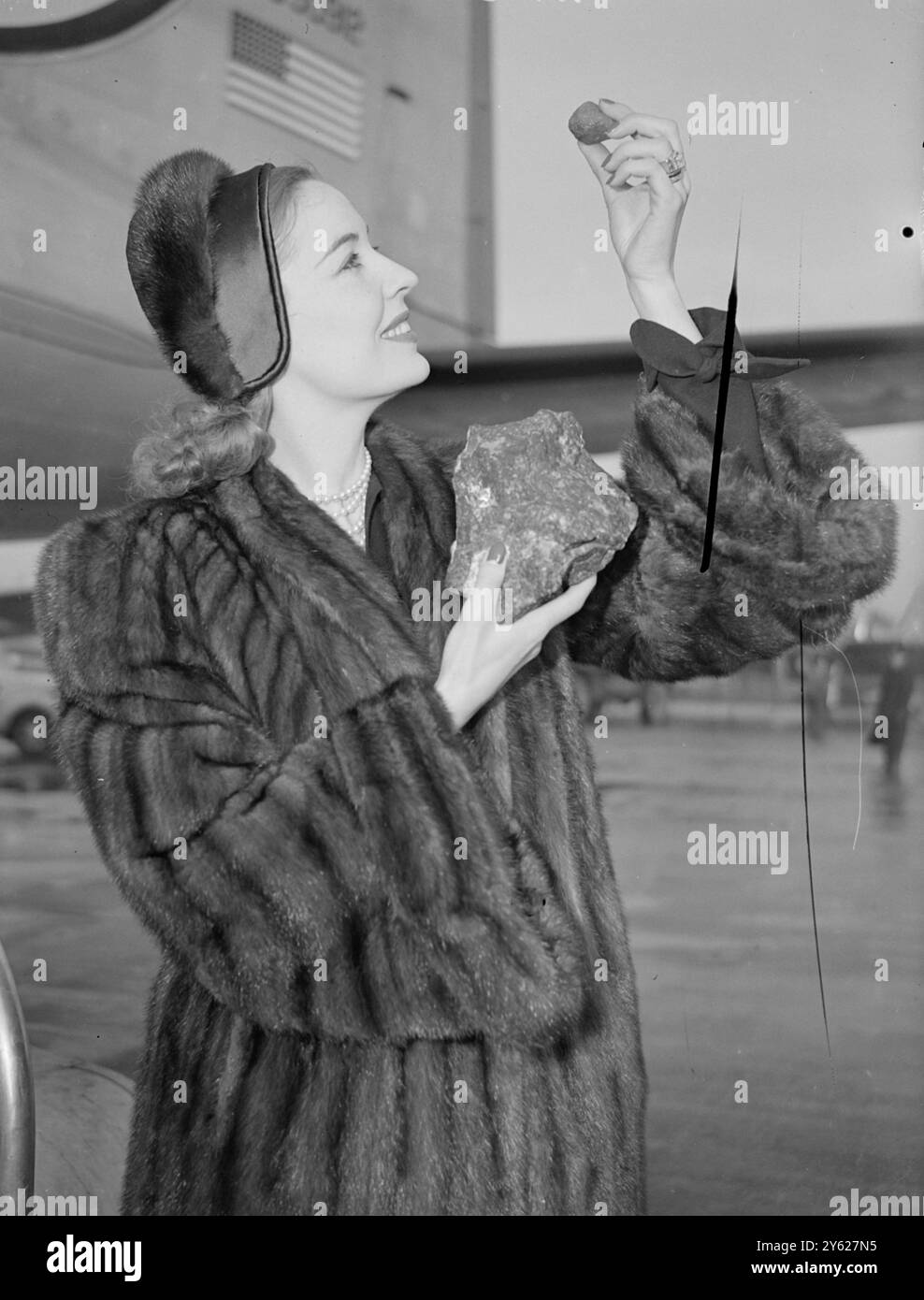 Zwei Industriediamanten im Wert von jeweils £2.000 wurden heute am Flughafen London von der Bühne Valerie Hobson an Bord eines Flugzeugs der American Overseas Airlines gebracht. Die Steine, einer der 250-karätige „Industrial Black Diamond“, der andere der 20-karätige „Industrial Yellow Cape Diamond“, sind auf dem Weg zur Industrial Diamond Convention in Atlantic City. Die Reise von New York zur Convention wird mit dem Hubschrauber erfolgen. Das Bild zeigt: Valerie Hobson bewundert heute Morgen den 20-karätigen Industrial Yellow Cape Diamond in seinem natürlichen Matrixhintergrund am Londoner Flughafen. Sie hält auch fest Stockfoto