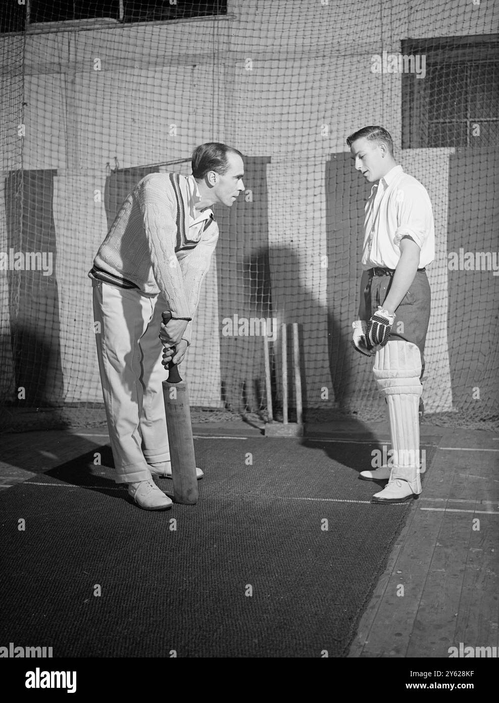 Die Hauptattraktion am Mittwochabend in Horefields, Bristol, sind die Coaching-Kurse, die von Mitgliedern des Gloucester County Cricket Teams in ihrem Club gegeben werden. Zu den „Schülern“ zählen fast alle, von Schülern bis hin zu Geschäftsleuten, die die Chance nutzen, erstklassige Cricket-Unterricht zu erhalten. Das Bild zeigt: J.F.Crapp, der führende Gloucester-Schläger, gibt dem 18-jährigen Charlie Hart vom Westerleigh Village Team ein paar „Tipps“ im Club. 17. Januar 1948 Stockfoto