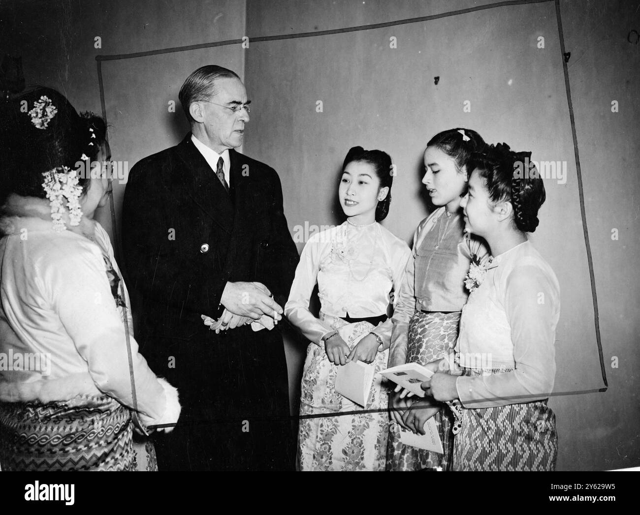 Die Nachfolge Birmas aus dem britischen Commonwealth of Nations und die Gründung der Union Birmas wurden heute Morgen in der birmanischen Botschaft auf dem Berkely-Platz gefeiert. Sir Stafford Cripps, Finanzminister, war anwesend, um im Namen der Regierung seiner Majestät zu sprechen und beim Hissen der neuen sechs Sterne rot-blauen Nationalflagge Burmas beizuwohnen. Das Bild zeigt: Sir Stafford Cripps, dargestellt mit burmesischen Mädchen in Nationalkleidung bei den heutigen Unabhängigkeitsfeiern in London. 3. Januar 1948 Stockfoto