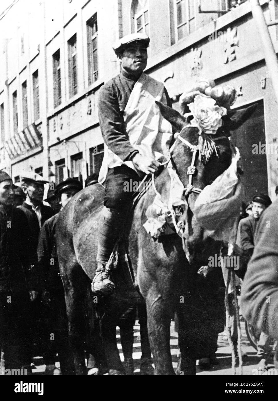 Das ist Red China. - Und Ehre für den Rekruten. Es ist schwer, die alte chinesische Idee loszuwerden, dass Soldat ein unehrenhafter Beruf ist, aber die Kommunisten zitierten, indem sie der Volksarmee neue Rekruten gaben, ein feierlicher Sendoff. Wie viele andere ist auch dieser neue Rekrut dekoriert und reitet als Ehrenzeichen auf einem dekorierten Pferd durch die Straßen von Harbin. - 13. Dezember 1947 Stockfoto