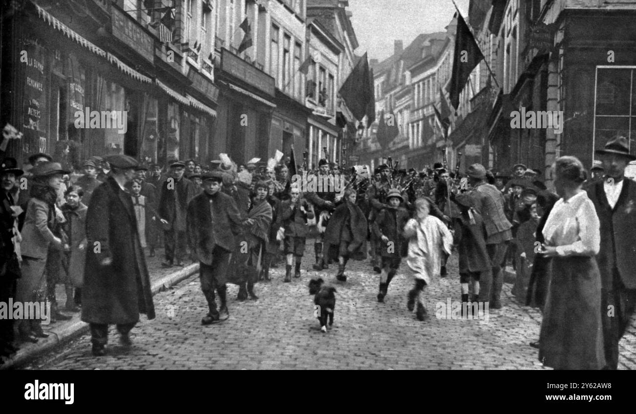 Unser Krieg endete dort, wo er begann: Mons und Poetic Justice, wo der historische Rückzug der Verachtungslosen 1914 begann. Mons am letzten Tag des Kampfes vor dem Waffenstillstand, Kanadier, angeführt von Pipern, die die Stadt betreten Stockfoto