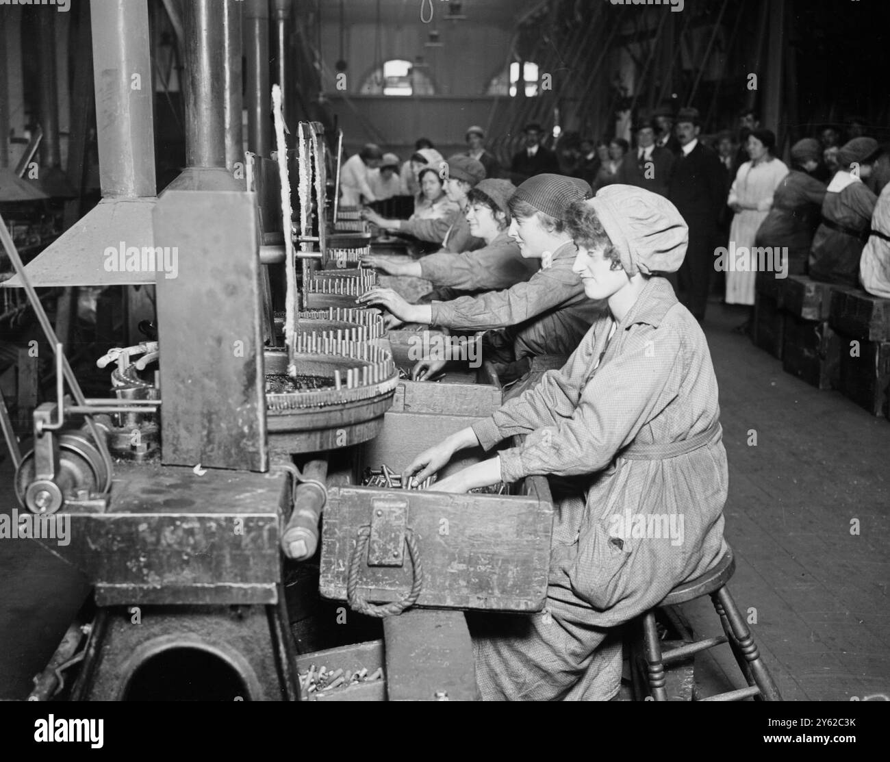 Ostern in Woolwich im Südosten Londons. Munition funktioniert über die Feiertage. Jungen, Mädchen, Frauen und Männer arbeiten an der Maschine, die die Blei-Kerne für Kugeln schneidet und die Kugeln formt und schneidet. Halbglühkartuschen. Dies geschieht an Drehmaschinen, die sie durch eine Flamme auf der Rückseite führen. 29. März 1918 Stockfoto