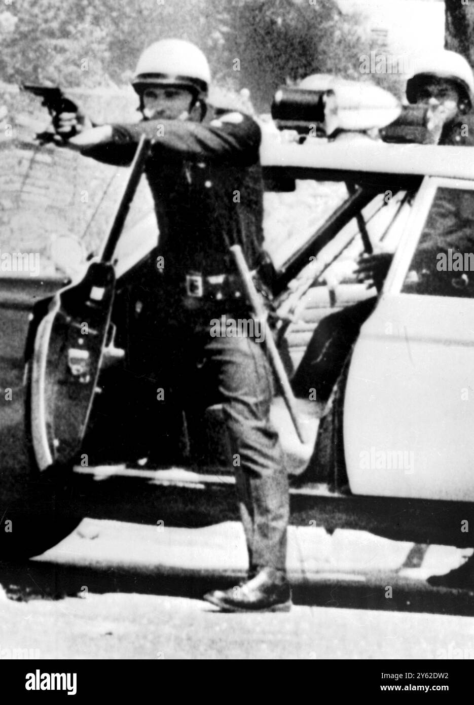 Los Angeles, Kalifornien: Hier wird ein Polizist von Los Angeles gezeigt, der die Tür seines Patrouillenautos benutzt, um seinen Schießarm zu halten, während er Randalierer abhält. Watts District von Los Angeles. Sechs Tage lang war das Gebiet mit Gewalt gefüllt. - 14. August 1965 Stockfoto