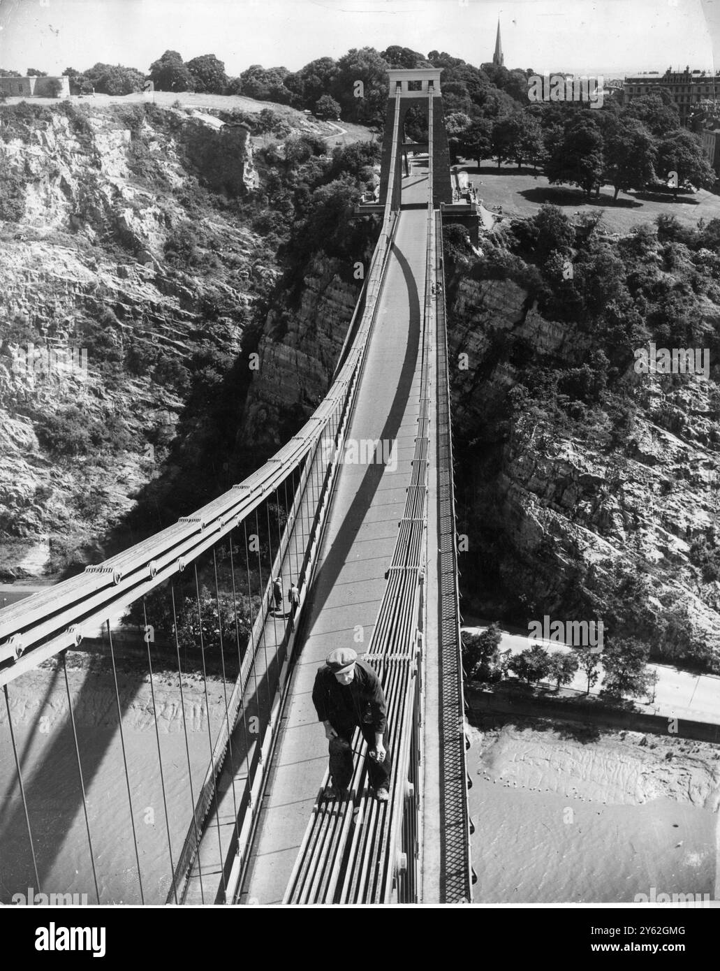 Die vielleicht höchste und coolste Ölarbeit Großbritanniens wird von diesem Arbeiter ausgeführt , der auf den steilen Ketten der Clifton Suspension Bridge 330 Meter über dem Fluss Avon bei Bristol , Gloucestershire , sicher sitzt . Er kontrolliert und ölt die Gelenke an den Ketten der Brücke. 3. Juli 1952 Stockfoto