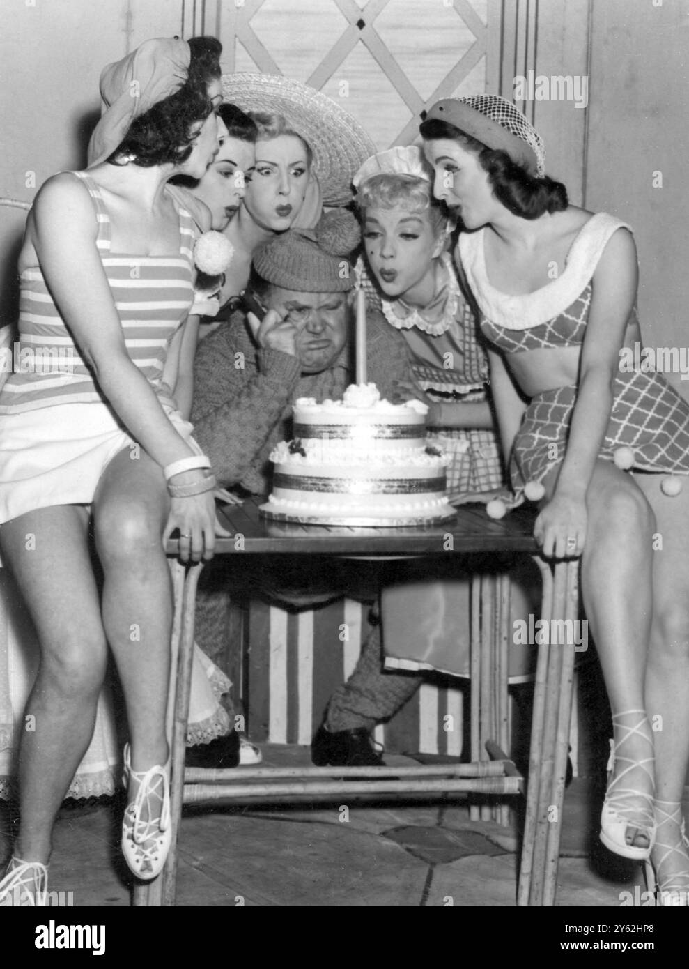 Obwohl der Komiker Fred Emney von wunderschönen Chormädchen umgeben ist, scheint er ihre Hilfe beim Ausblasen der Kerze auf der Geburtstagskuche nicht zu schätzen. Er ist der Meinung, dass er, wenn es etwas zu tun gibt, genau der richtige Mann für den Job ist. Die einsame Kerze auf dem Kuchen repräsentiert den ersten Geburtstag der Show BLUE FÜR Einen JUNGEN im His Majesty's Theatre in London. ©TopFoto Stockfoto