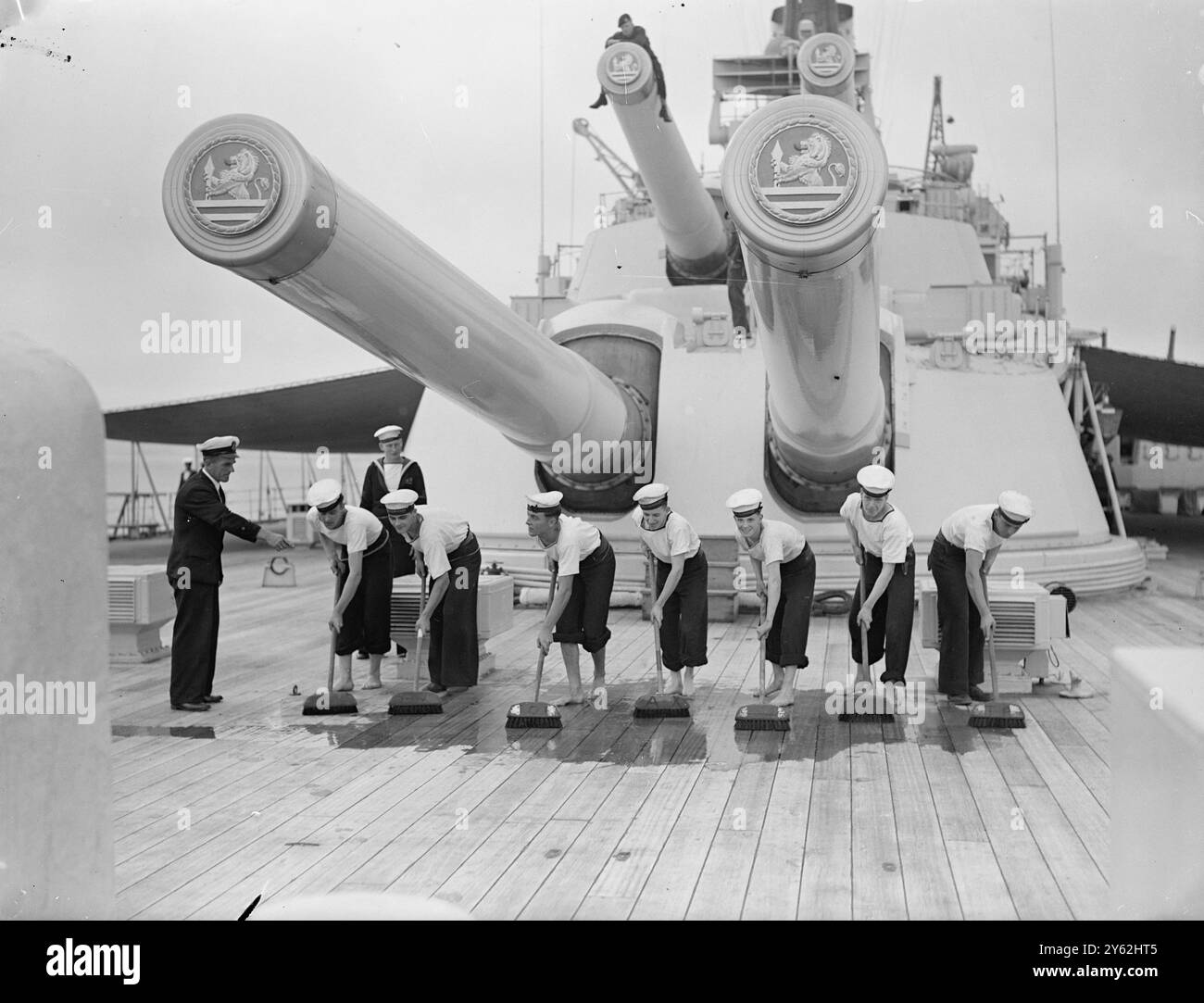 Avantgarde bereitet sich auf die Royal Australian Tour vor. Die Besatzung der HMS Vanguard freut sich mit großer Vorfreude auf die Royal Tour durch Australasien im nächsten Jahr und ist zu Recht stolz auf ihre Verbindung mit diesem großartigen Schiff, das jetzt in der Weymouth Bay (Dorset) liegt. Vor einer Shakedown-Kreuzfahrt nach Gibraltar und Malta am nächsten Freitag. Das Schiff erhält den letzten Schliff für die Tour, als es nach Devonport zurückkehrt. Das Bild zeigt: Mitglieder der Besatzung der Vanguard sind mit dem Schrubben und Waschen des Daches beschäftigt. 10. September 1948 Stockfoto
