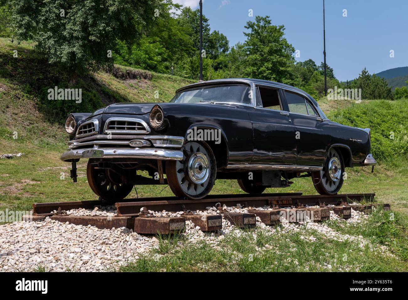 Mokra Gora, Serbien - 22. Juni. 2023: Retro-Auto Chrysler New Yorker Deluxe mit Laufrädern, die für das Fahren auf Bahnschienen vor Schmalspurwagen modifiziert wurden Stockfoto