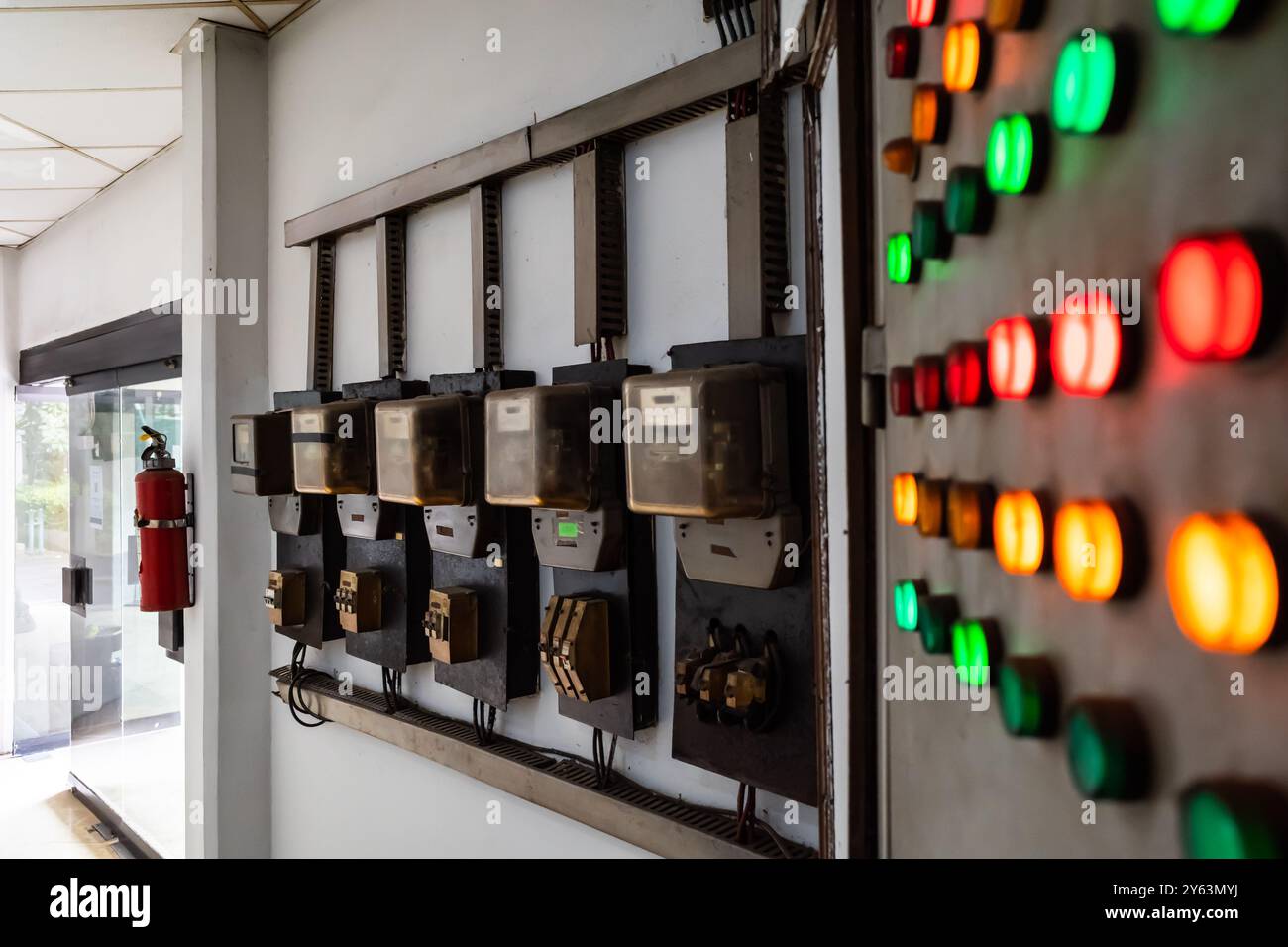 Alte Anordnung des Stromkreises für kWh-Zähler mit alter und rustikaler elektrischer Schalttafel mit roten, grünen und gelben Leuchten in einem Gebäude Stockfoto