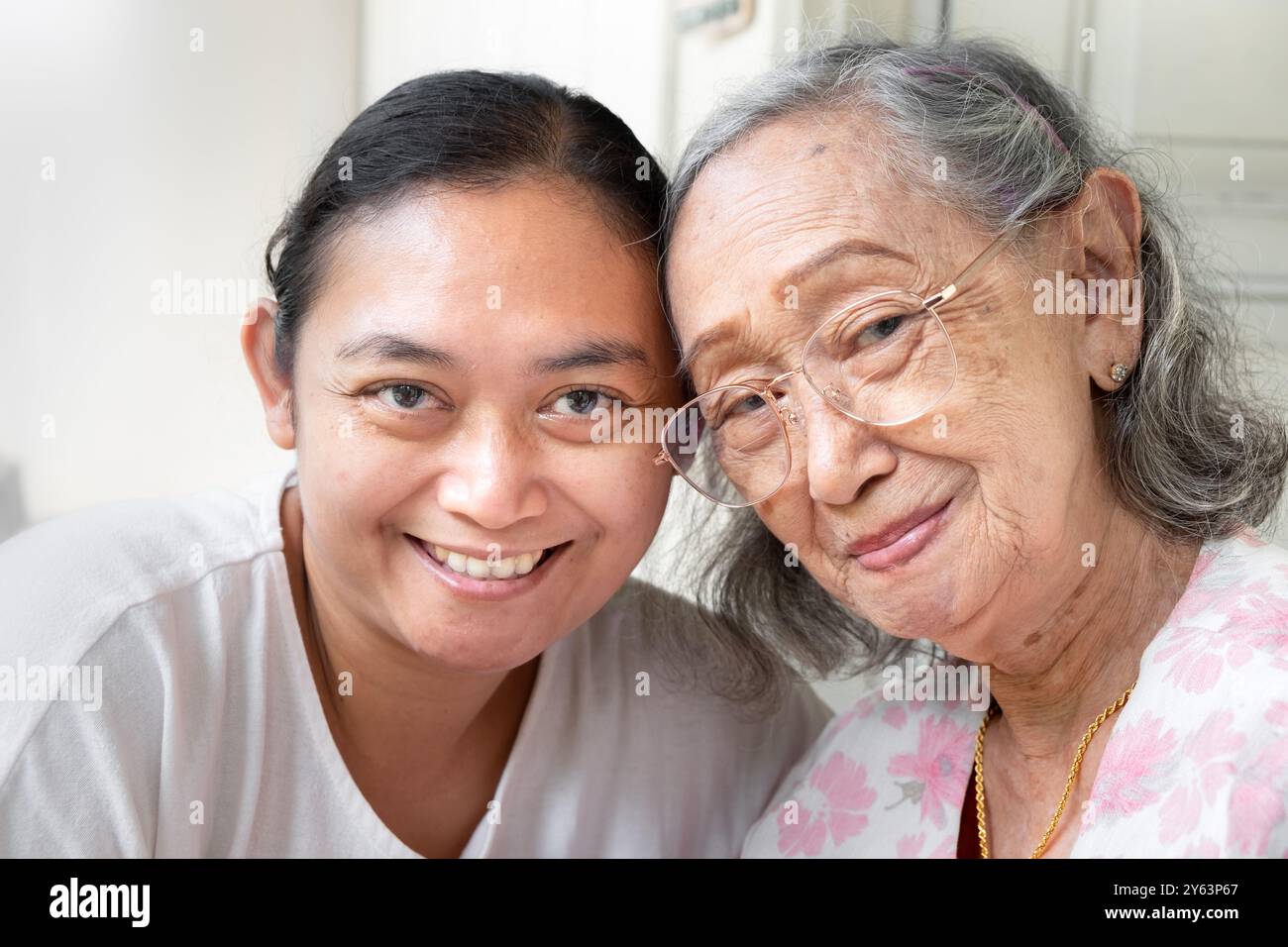 Gesunde und glückliche asiatische Seniorin zusammen mit reifer erwachsener Tochter posiert vor der Kamera Stockfoto