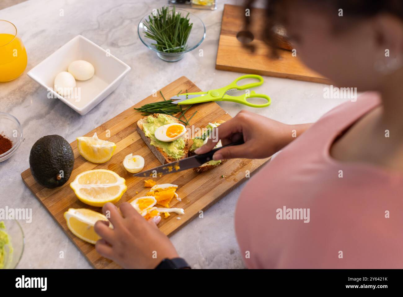 Gesunde Mahlzeit zubereiten, Frau schneiden Zitrone und gekochte Eier auf Schneidebrett, zu Hause, zu Hause Stockfoto