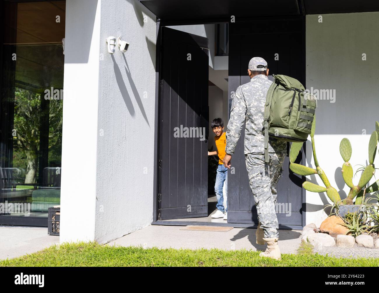 Zurück nach Hause, Soldat in Uniform mit Rucksack, begrüßt von einem jungen Sohn an der Tür, Kopierraum Stockfoto