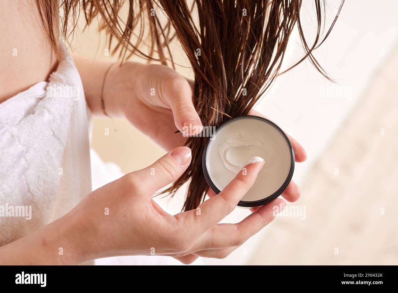 Person, die die Haarmaske auf nasses Haar aufträgt, Nahaufnahme von Händen und Haaren. Stockfoto