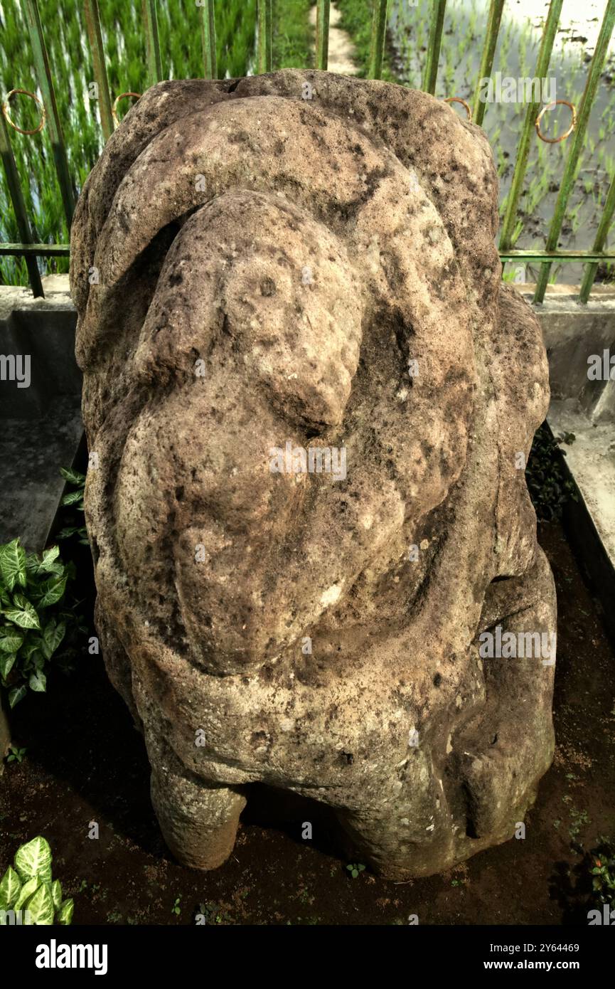 Megalithskulptur in Form einer menschlichen Figur, die um eine Schlange im Dorf Tanjung Aro, Pagar Alam, Südsumatra, Indonesien, gewickelt ist. Stockfoto