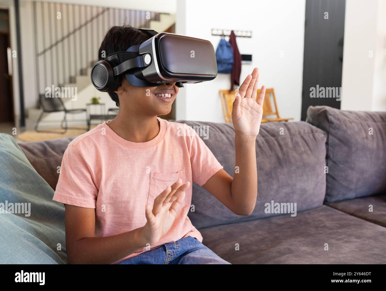 Mit dem VR-Headset sitzt der indische Junge auf der Couch und spielt Virtual-Reality-Spiel Stockfoto