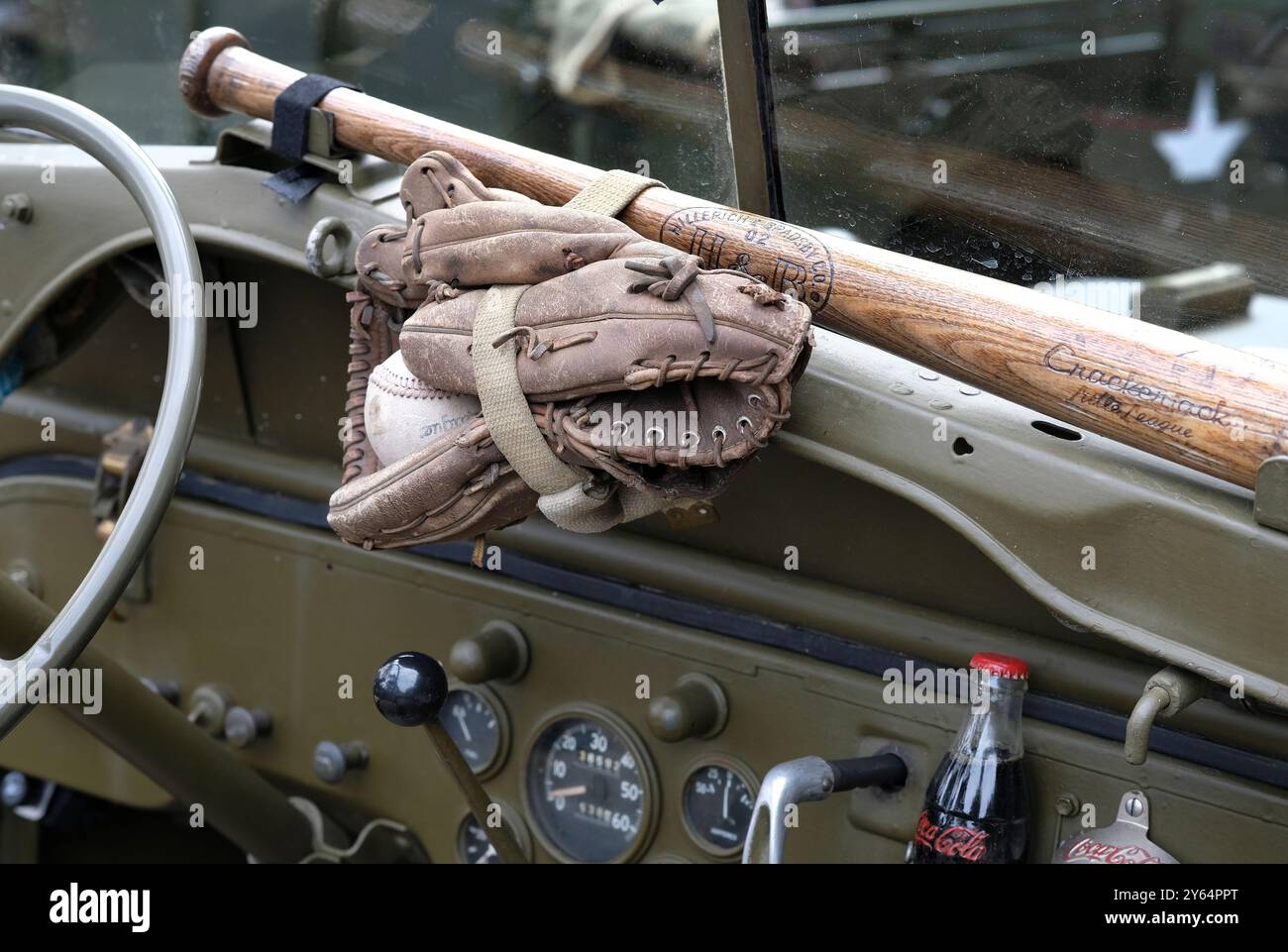 Baseballschläger, Handschuhe und Ball auf dem Armaturenbrett eines alten Militärjeeps Stockfoto