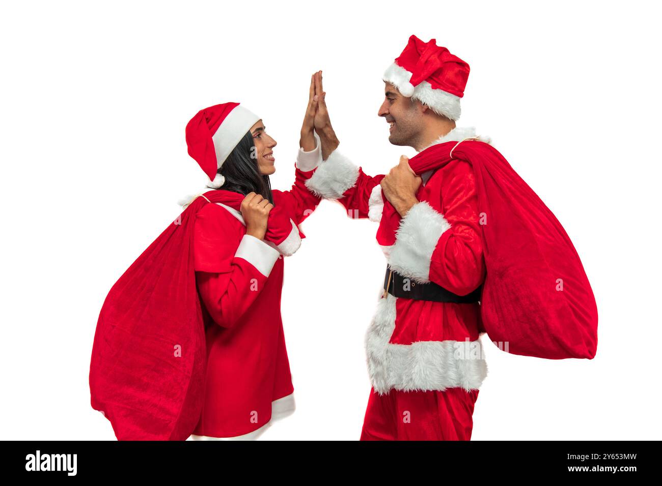 Fröhliches Paar in Weihnachtsmannskostümen gibt sich gegenseitig eine freundliche High-Five, die gemeinsam den Feiertagsgeist in festlicher Atmosphäre feiert Stockfoto