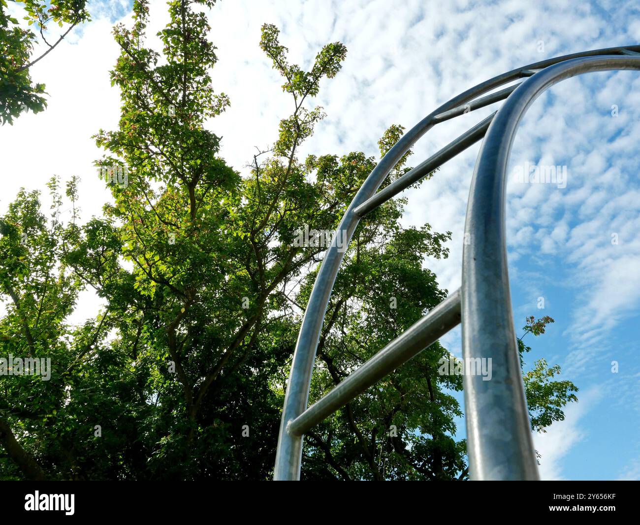 Eine Bogenleiter, die in den Himmel reicht. Das Motiv, das auf einem öffentlichen Spielplatz festgehalten wurde, lädt als Leiter zum Himmel zu kreativen Interpretationen ein. Stockfoto