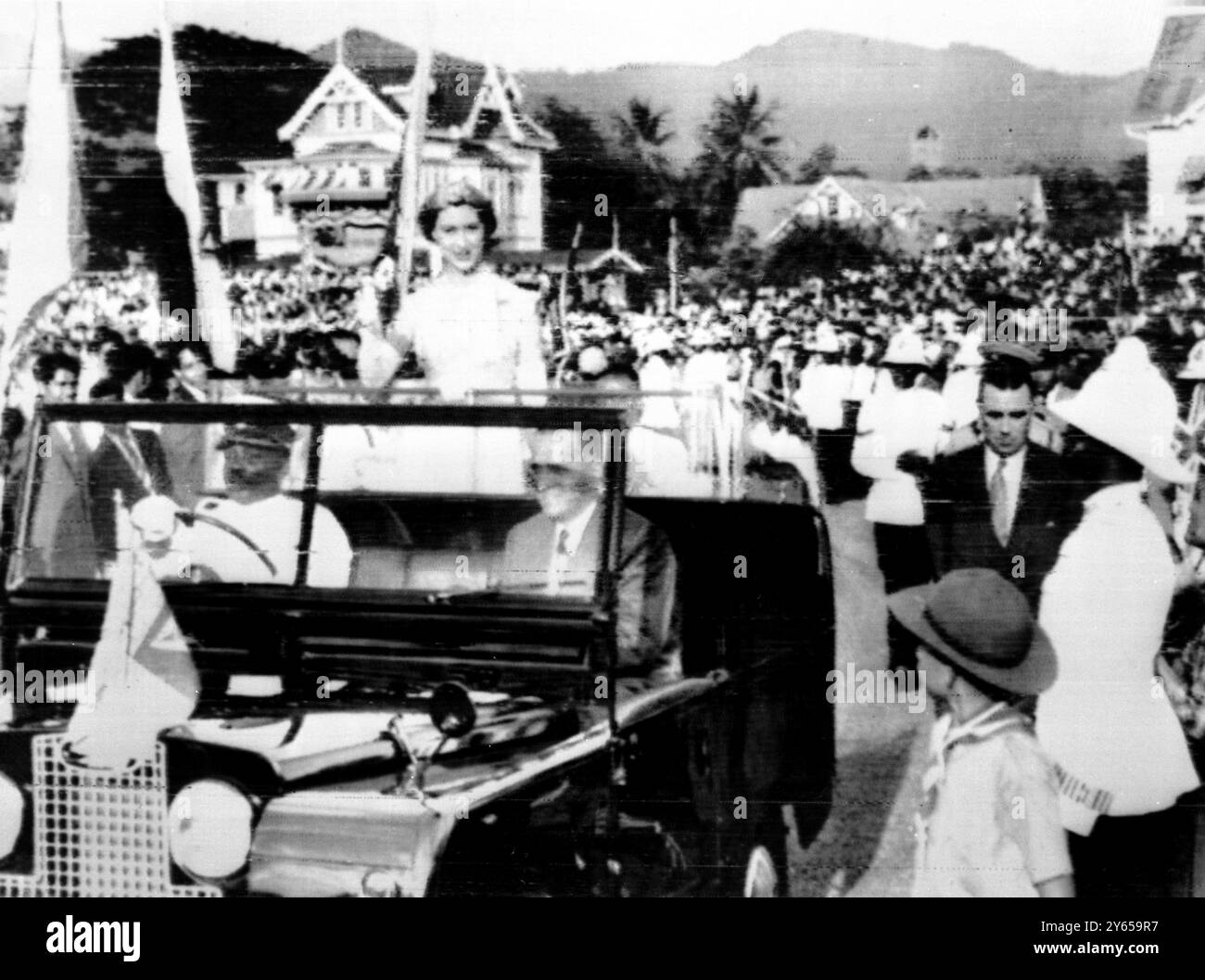 Prinzessin Margaret steht in einem Land Rover und lächelt fröhlich und winkt 30 000 Kindern zu, die sie im Queen's Park Cricket Club Oval begrüßen. Der Fahrer ist Polizeikorporal Francique und neben ihm der Bildungsminister von Trinidad Roy Joseph . 4. Februar 1955 Stockfoto