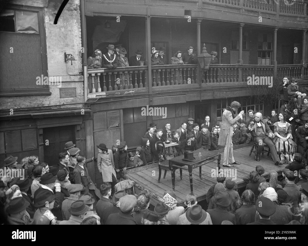 Die Tabard Players gaben eine Open-Air-Performance von Szenen aus David Copperfield im Innenhof des George Inn , Borough High Street , London . Als Bühne diente ein LKW. Das George Inn wird in Dickens ' Little Dorrit ' erwähnt. Allgemeine Sicht auf den ersten Akt im Gange, beobachtet von einem Publikum im innenhof und auf den alten Balkonen. Auf der linken Seite wird David Copperfield von Richard James, einem 21-jährigen Angestellter von Sutton, Surrey, gespielt . - 9. Februar 1946 Stockfoto