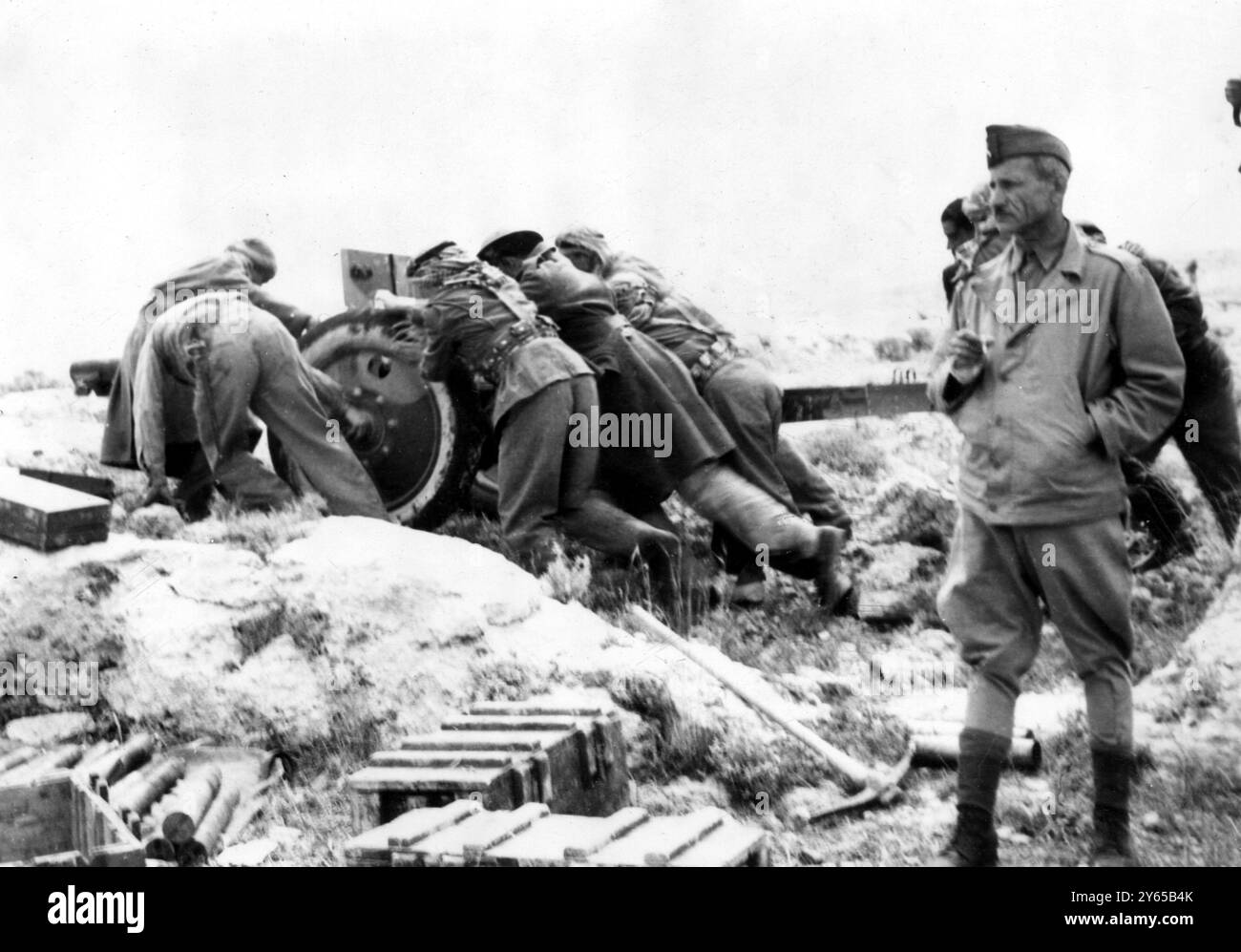 Juden und Araber in ' Schlacht um die Lebensader ' - bittere Kämpfe um die Autobahn Tel Aviv . Fotoshows : Mahmoud Bey Mahdi , syrischer Befehlshaber des Zentralen Gebiets , Arabische Befreiungsarmee , gesehen ( rechts vorne ) im Schlachtgebiet bei Latrun , etwa 24 Meilen von der Neustadt Jerusalem entfernt entlang der Tel Aviv Autobahn - der jüdischen Lebensader - während Mitglieder eines Geschützteams gesehen werden , wie sie ihre Waffe näher zum Ziel bewegen . In diesem Gebiet finden jetzt bittere Kämpfe statt, die als " Schlacht um die Lebensader " bezeichnet werden. 31. Mai 1948 Stockfoto