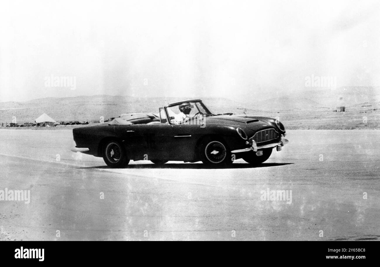 Der sportliebende König Hussein von Jordanien , der am Lenkrad seines Aston Martin zu sehen ist , wird nächsten Monat Großbritannien für einen zehntägigen Staatsbesuch besuchen . Er wird von seiner in Bristisch geborenen Frau Prinzessin Muna begleitet. 28. Juni 1966 Stockfoto