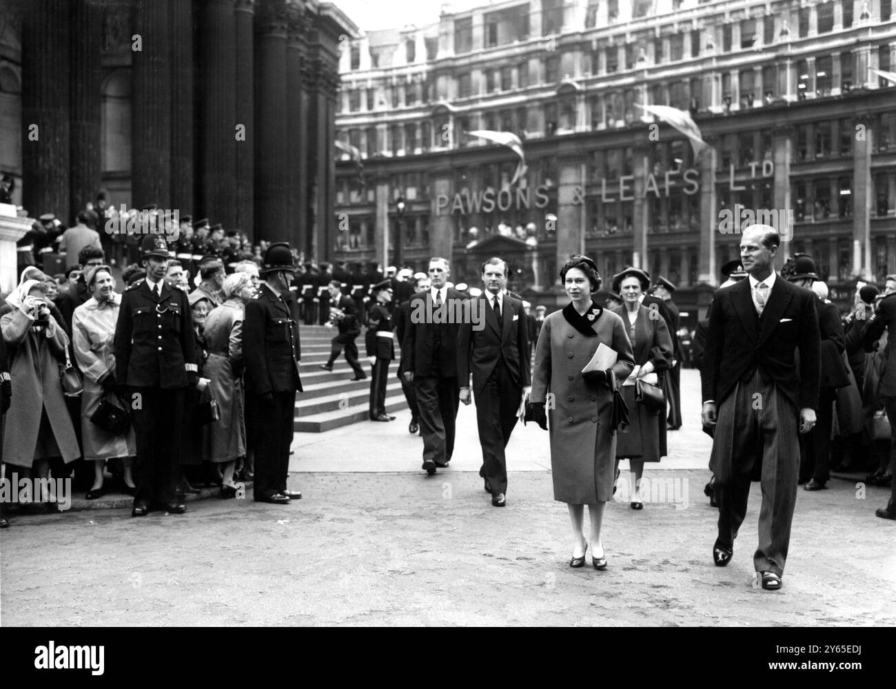 Die Königin und der Herzog von Edinburgh lächeln die Menschenmassen der Stadt an, während sie von der St Paul's Cathedral zum Kapitelhaus zum Mittagessen laufen. Sie hatten an der Wiedereinweihung in der Cathedral of the High Altars teilgenommen, die durch Londons Bombenangriffe beschädigt wurde. Sie gedenkt nun an die Männer und Frauen des Commonwealth , die ihr Leben in zwei Arbeitskriegen gaben . Der Gottesdienst markierte die Wiedereröffnung der gesamten Kathedrale (mit Ausnahme des nördlichen Querschiffes) nach 17 Jahren Wiederaufbau. Mai 1958 Stockfoto