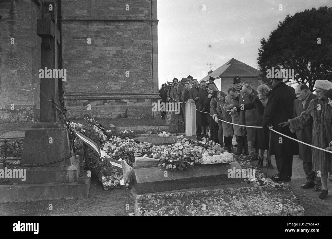 Sir Winstons Grab Eine Dame in der Reihe der Besucher von Sir Winstons Grab zeigt auf die Blumen auf dem Grab von Sir Winston Churchill , der auf dem Friedhof der St. Martin's Church begraben wurde . 31. Januar 1965 Stockfoto