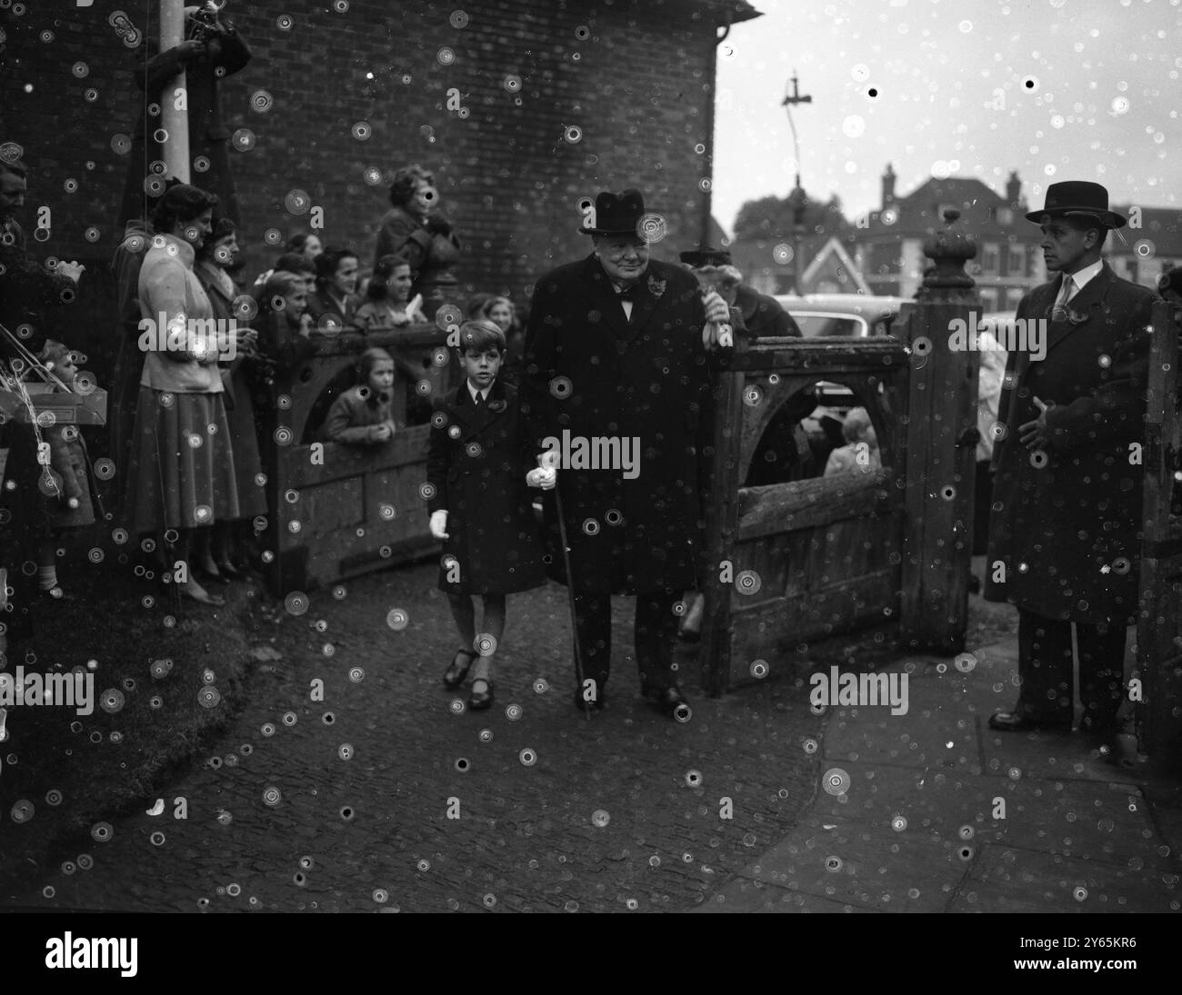 Premierminister Sir Winston Churchill mit Enkel Nicholas Soames , der zur Taufe seiner jüngsten Enkelin Charlotte Clementine Soames in der Westerham Parish Church eintraf . Das Baby ist die Tochter von Captain Christopher Soames und der ehemaligen Mary Churchill , die drei weitere Kinder haben . 6. November 1954 Stockfoto