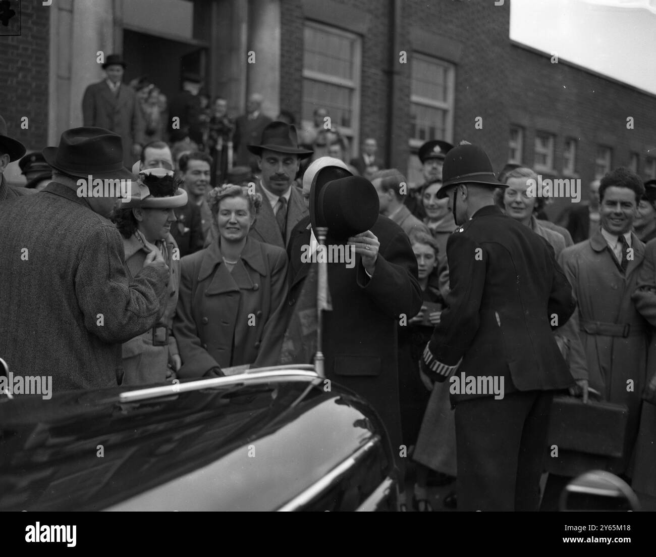 Die Menschenmassen loben Herrn Churchill nach seinem Sieg in Woodford , WER IST DER MANN HINTER DEM HUT " . Es ist Herr Winston Churchill , wahrscheinlich neuer Premierminister Großbritanniens , der die St Barnabas School in Woodford nach der Stimmenzählung verlässt . Oktober 1951 Stockfoto