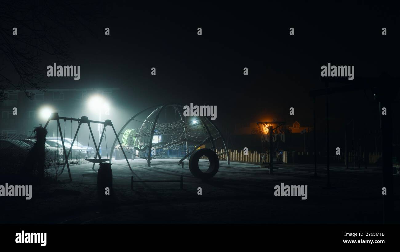 Ein gruseliger Spielplatz in einer kalten, nebligen atmopsherischen Winternacht. Mit niemandem in der Nähe. Stockfoto