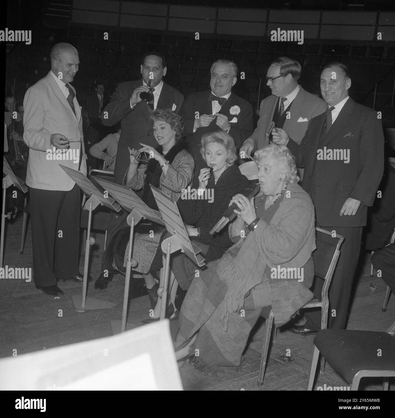 Herr Herman Lindars , Dirigent des Royal Philharmonic Orchestra , dirigiert die Gruppe von sieben berühmten Persönlichkeiten bei der Probe auf verschiedenen Musikinstrumenten , die sie an diesen Abenden spielen werden Haydn's , " Toy Symphony " mit dem Orchester in der Royal Albert Hall in London das Konzert wird mit Hilfe des " Toy for the Sick Child " Fonds durchgeführt . Bild von links nach rechts , hintere Reihe ; berühmter Dance Band Leader , Edmundo Ros ( Trompete) , TV Persönlichkeit , Lord Boothby ( Quail) , TV Persönlichkeit , Cliff Michelmore ( Schlagzeug ) , ehemaliger England Cricket Captain Sir Len Hutton (Rattle). Abgebildet – f Stockfoto
