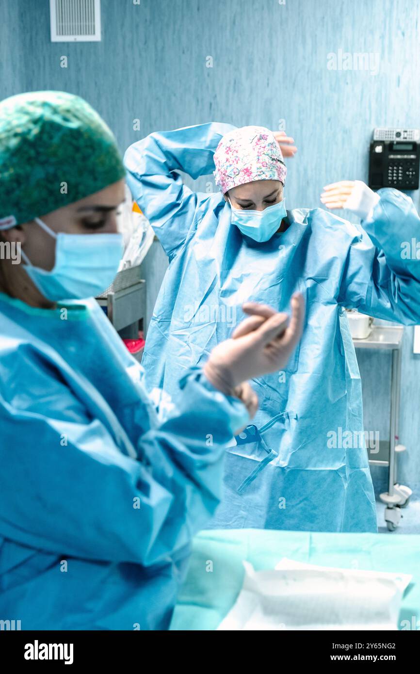 Zwei Chirurgen in Peelings und Masken bereiten sich auf einen Eingriff in einem Krankenhaus-OP vor und konzentrieren sich auf ihre Aufgaben unter sterilen medizinischen Geräten Stockfoto
