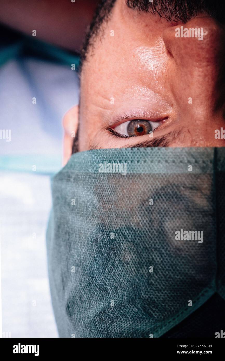 Ein detailliertes Nahaufnahme-Foto, das den intensiven Blick einer Person zeigt, die im Krankenhaus eine OP-Mütze trägt, wobei der Fokus und die Vorbereitung betont werden Stockfoto