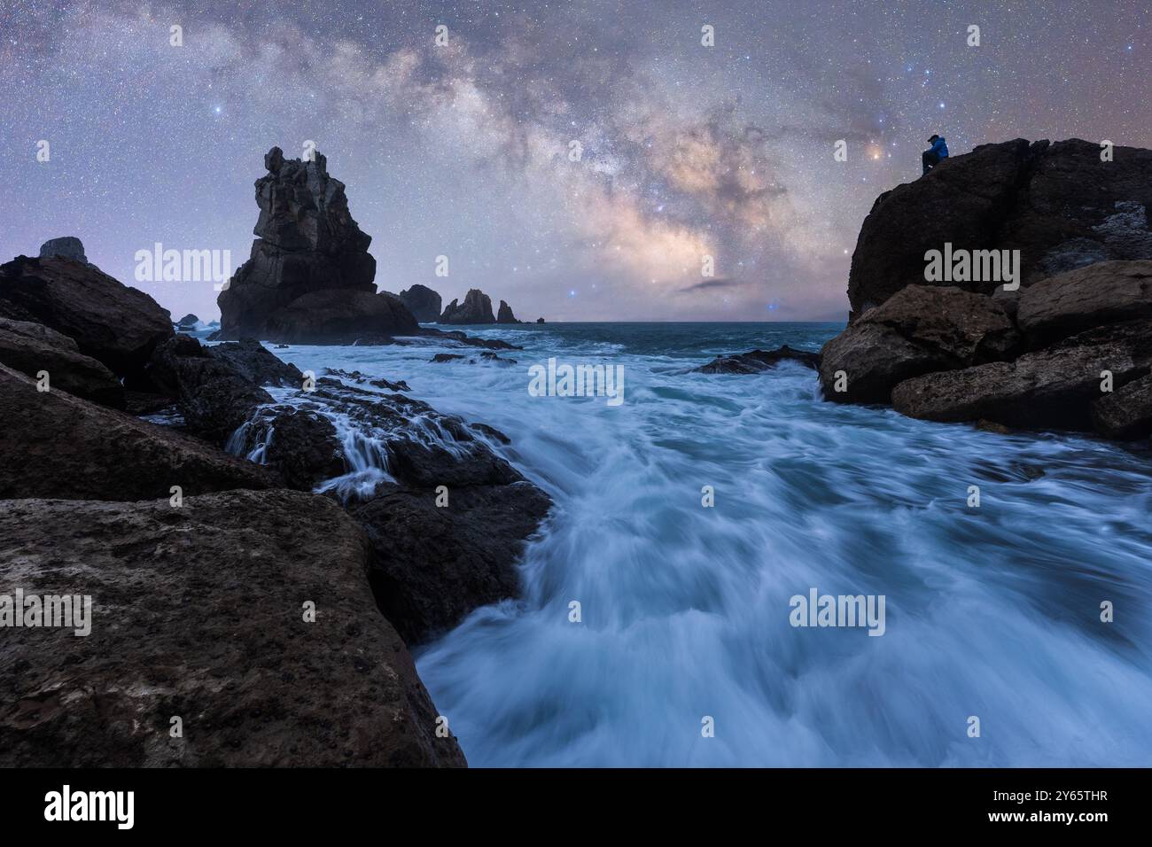 Atemberaubende Nachtaufnahmen der Milchstraße über der zerklüfteten Küste von Almeria Sirens Reef, mit Wellen, die an den felsigen Küsten unter einem Sternenhimmel krachen Stockfoto