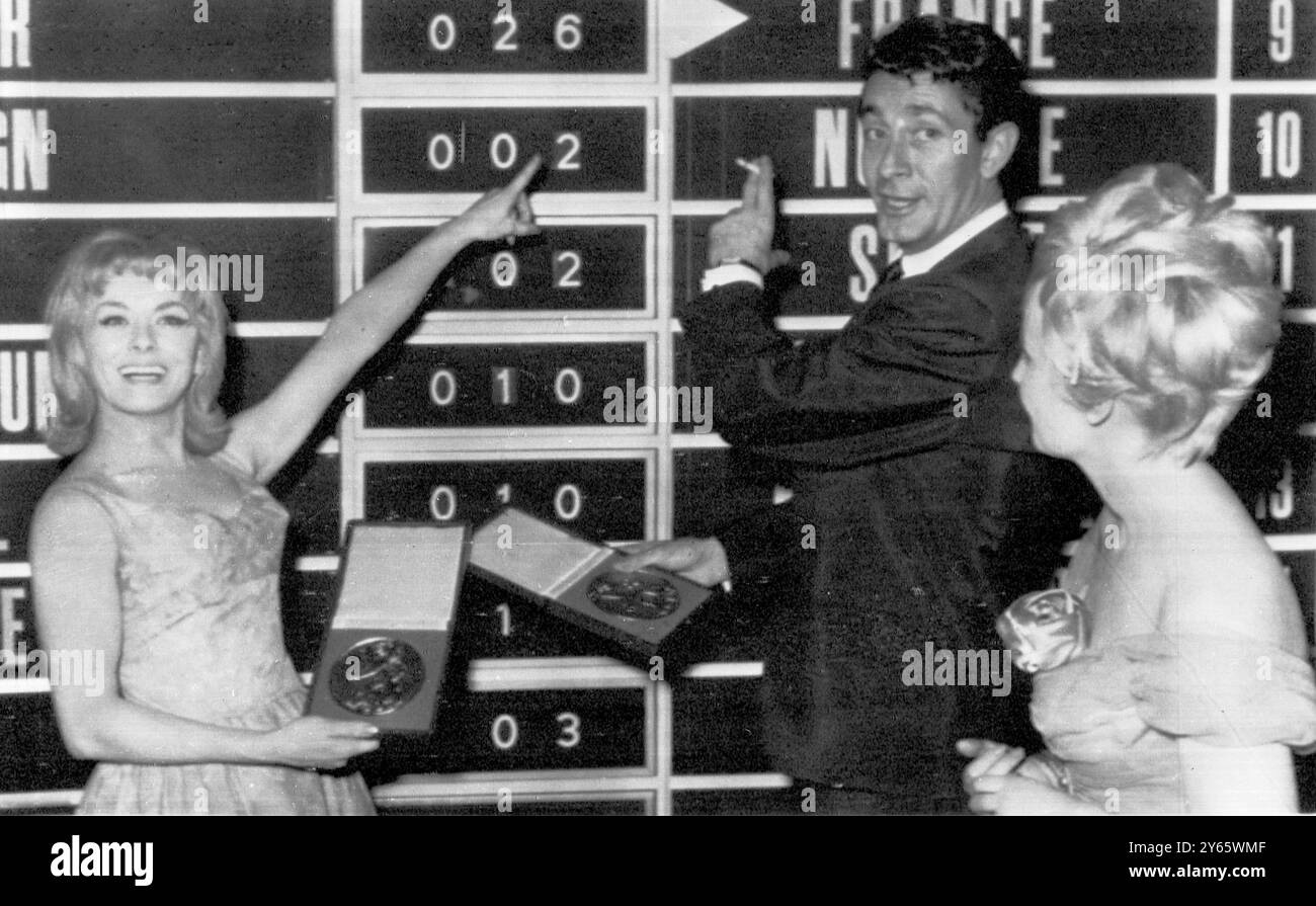 Die französische Sängerin Isabelle Aubret (links) weist auf die sechsundzwanzigste Zahl der Stimmen hin, die sie gesammelt hat, um den Eurovision Song Contest zu gewinnen. Im Zentrum steht Jean Claude Pascal , Gewinner des letztjährigen Grand Prix . Luxemburg 19. März 1962 Stockfoto