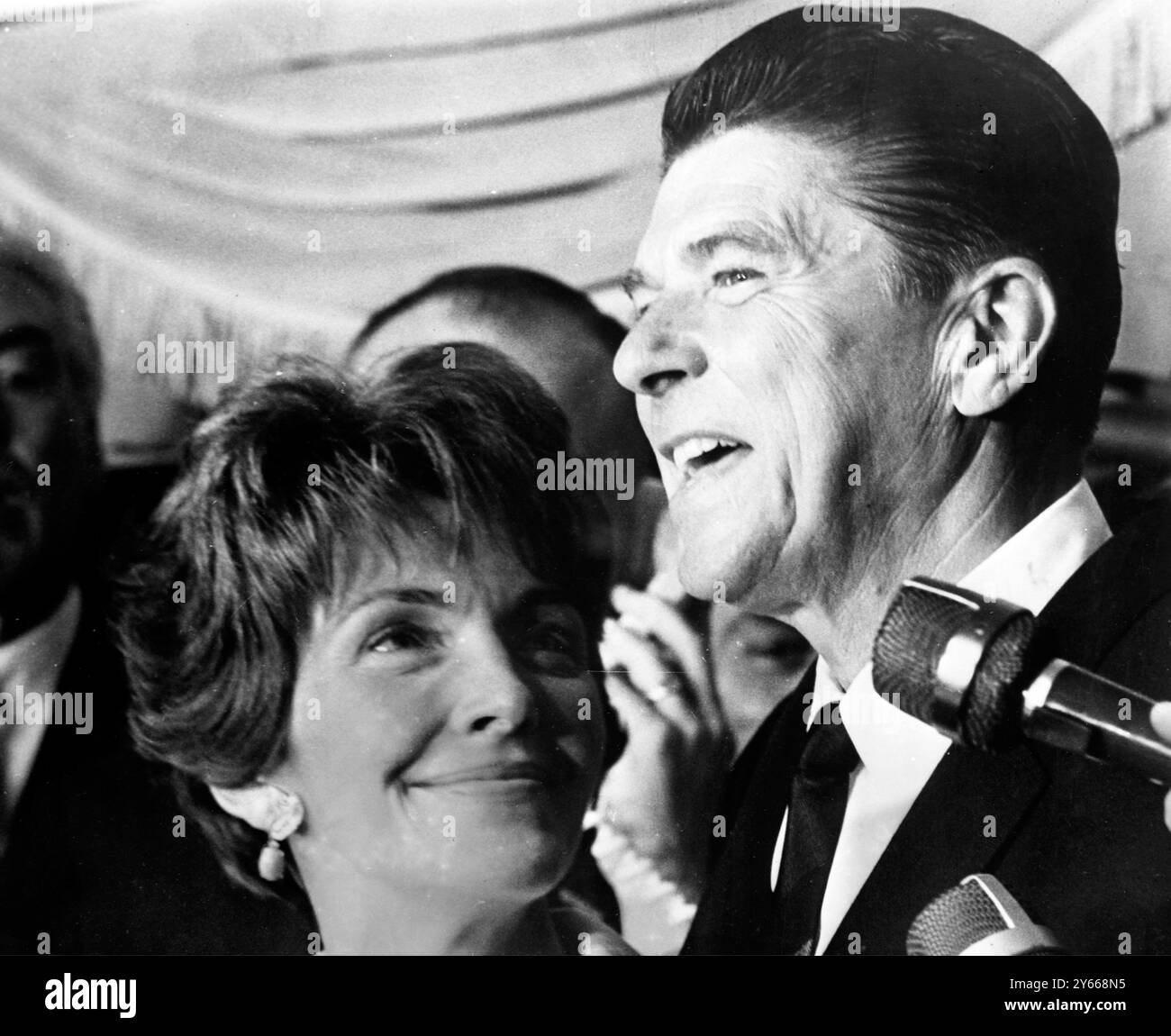 A Happy Ronald Reagan spricht mit Nachrichtensprechern , nachdem er am 7 . Juni 1966 die republikanische Nominierung zum Gouverneur in den kalifornischen Vorwahlen eingenommen hatte . Reagans Ehefrau Nancy sieht stolz zu, wie ihr Ehemann seine Kampagne gegen den demokratischen Kandidaten Edmund ( Pat ) Brown skizziert. Reagan , ein Film- und Fernsehdarsteller , gewann einen überwältigenden Sieg und trat am .11. Juni 1966 als führende Figur in der Republikanischen Partei hervor Stockfoto