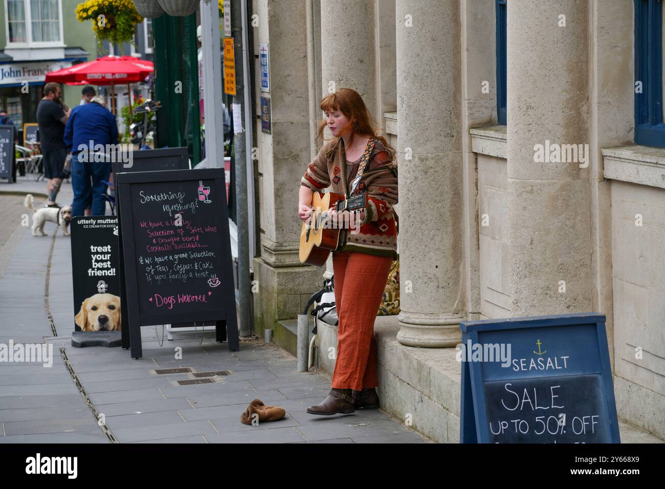 Tenby, Pembrokeshire, Wales - 1. Juli 2024: Eine junge, rothaarige Buskerin unterhält Einheimische und Touristen in der Hauptstraße von Tenby Stockfoto