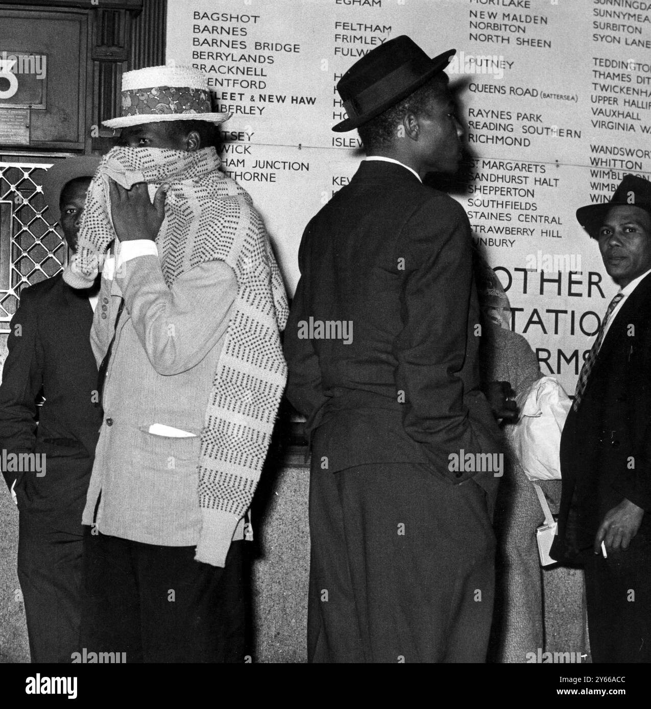 Ein Westindianer dämmte sich gegen das Marschwetter in London, als er mit anderen Einwanderern auf der Waterloo Station ankam. Er gehörte zu einer Gruppe von 790 Personen, die am 25. März 1962 an Bord des italienischen Linienschiffes Ascania in Southampton ankamen Stockfoto