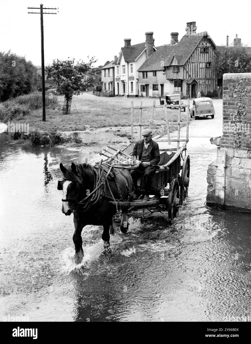 Ein alter Mann, der in Eynsford mit Pferd und Wagen durch den ford fährt. Zwischen den Kriegen Stockfoto