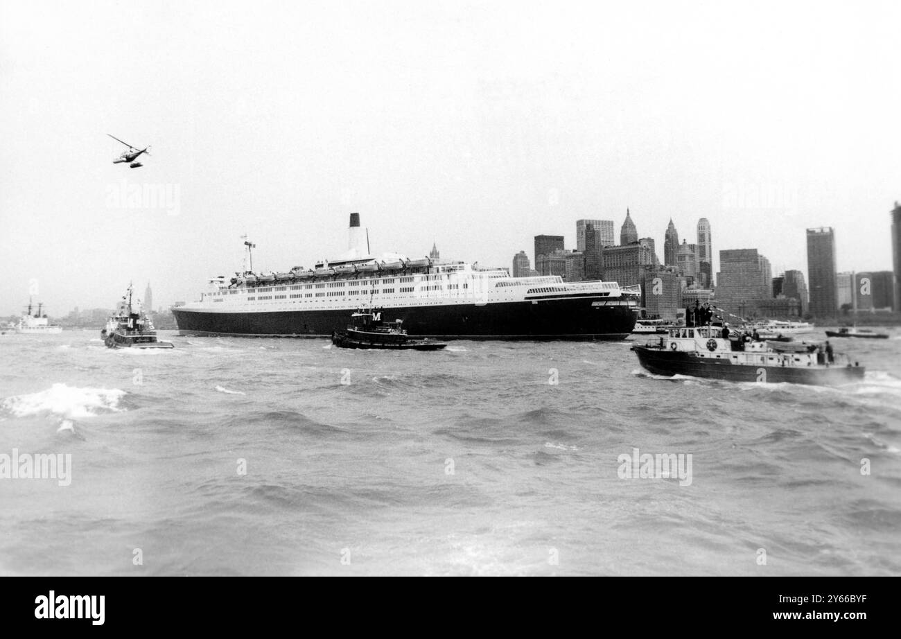 New York – Cunards luxuriöser Pasenger-Liner QEII bekommt ihren ersten Blick auf die berühmte Skyline von New York. New Yorker sehen zum ersten Mal das große Seeschiff, als sie in den Hafen gleitet. Die QEII wurde nach ihrer Transatlantischen Jungfernreise von kleinen Schiffen und „Luftgewandten“ begrüßt. Mai 1969 Stockfoto