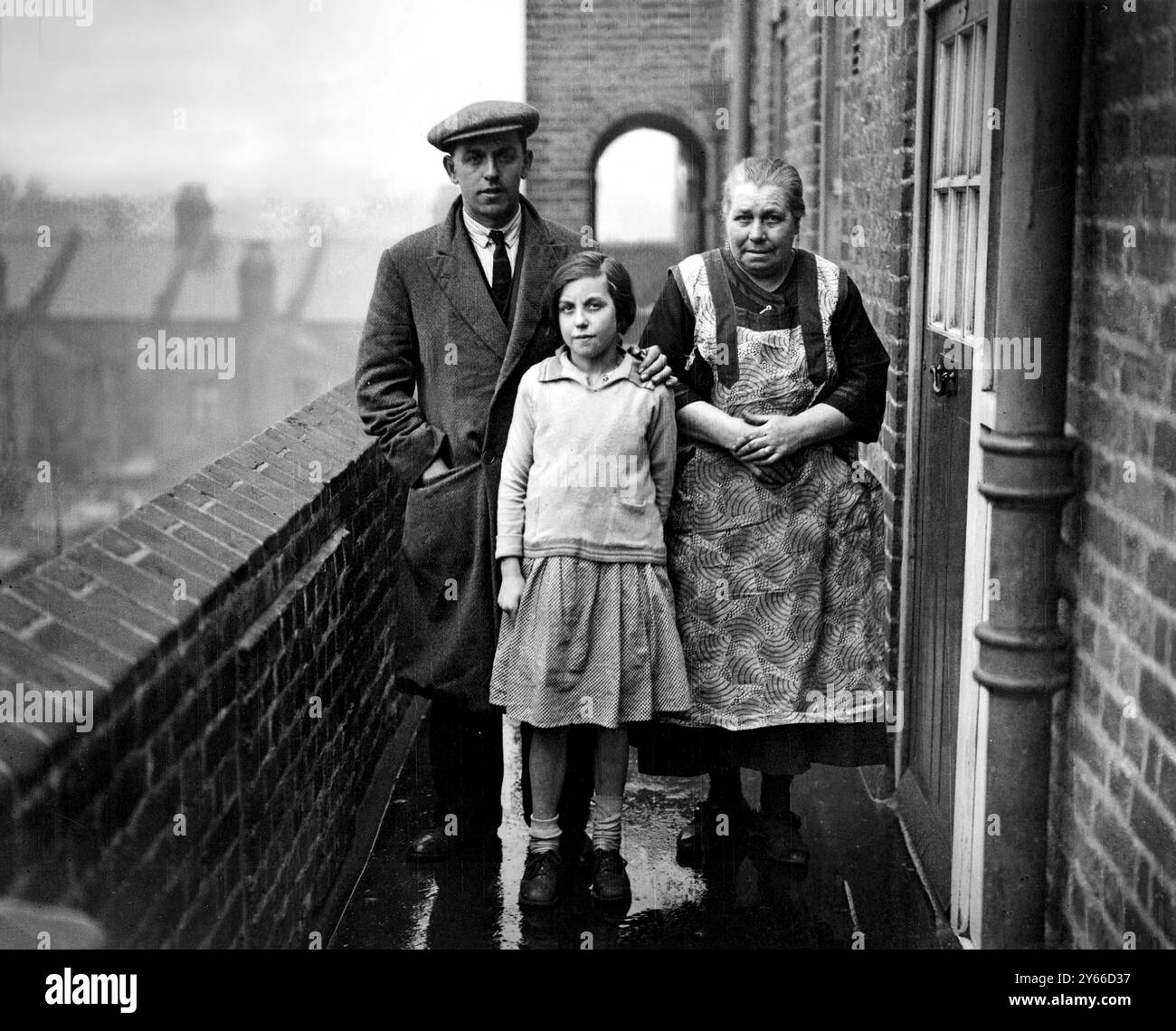 Mr. Jack Williamson mit seiner Tante Mrs. Anne Crawford und einem seiner sieben Kinder. Mr Williamson wurde von Gerichtsvollziehern des London County Council aus dem Wakefield House auf einem Anwesen in Peckham vertrieben, weil er einen Teil seiner Wohnung an seine Tante vermietet hatte. Es verursachte einen Konflikt mit Arbeitslosen und der Polizei, nachdem die Familie im Regen obdachlos gelassen wurde und ihre Möbel auf die Straße geworfen wurden. März 1932 Stockfoto