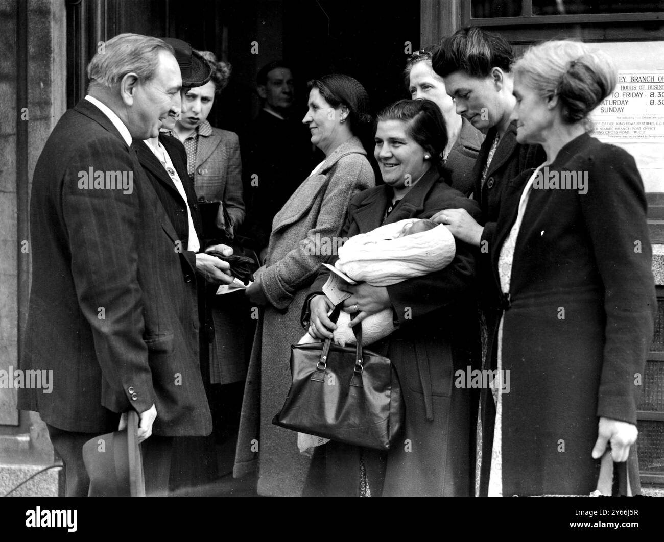 Die Zahlung der Familienzulagen begann heute Morgen. James Griffiths, Minister für nationale Versicherung, war in Begleitung seiner Frau im Postamt von Stepney im East End von London, um den ersten Empfänger zu begrüßen. Das Bild zeigt, wie Herr und Frau Griffiths (links) heute Morgen (Dienstag) einige der ersten Empfänger der Familienbeihilfe im Postamt der Filiale Stepney begrüßen. Mrs. Mary Ann Hall, Mutter von sechs Kindern, (im hellen Mantel, im Gespräch mit Mrs. Griffiths), war die erste, die heute ihr Geld in Stepney erhielt. August 1946 Stockfoto