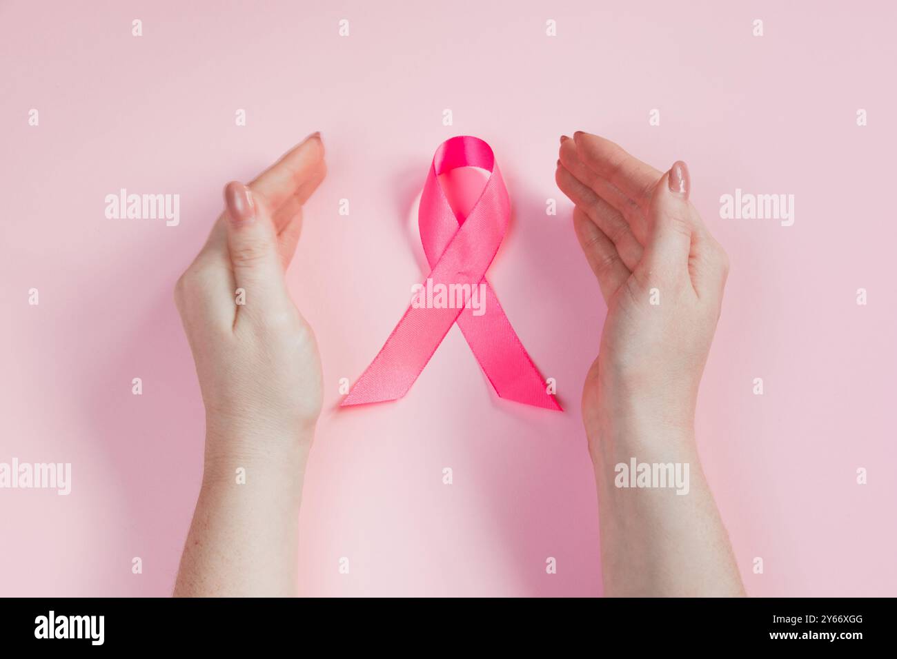 Monat Des Brustkrebsbewusstseins. Die Hand der Frau hält ein rosa Band. Gesundheitskonzept, Symbol zur Krebsbekämpfung. Speicherplatz kopieren. Stockfoto