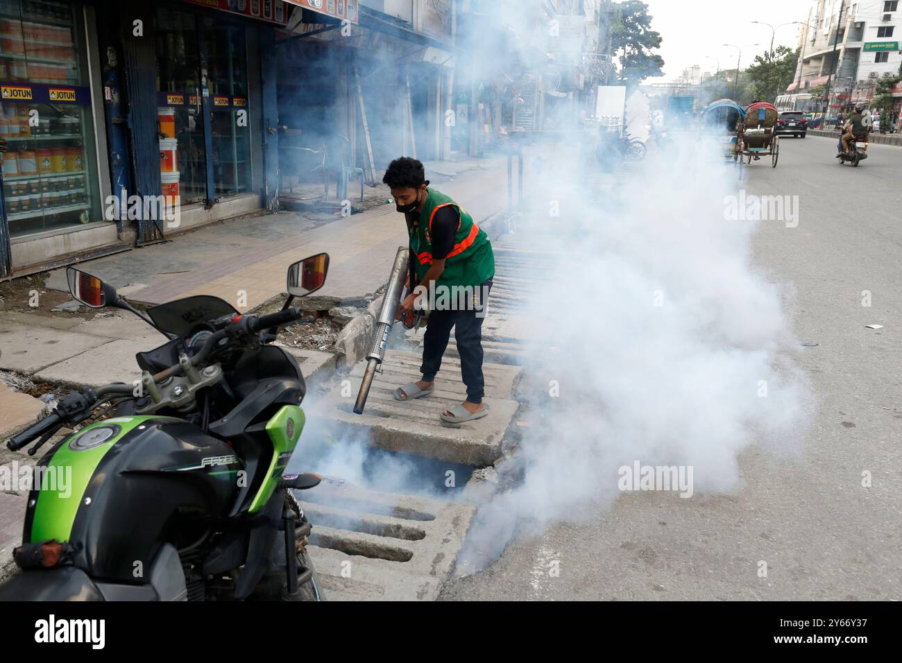 Dhaka, Bangladesch – 24. September 2024: Ein Arbeiter der Dhaka North City Corporation sprüht Mückenschutzmittel auf einen offenen Graben und eine Straße bei Badda in Dhaka Stockfoto