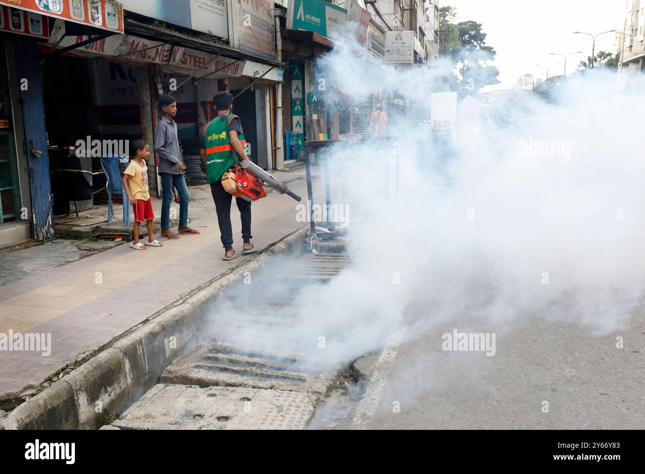 Dhaka, Bangladesch – 24. September 2024: Ein Arbeiter der Dhaka North City Corporation sprüht Mückenschutzmittel auf einen offenen Graben und eine Straße bei Badda in Dhaka Stockfoto
