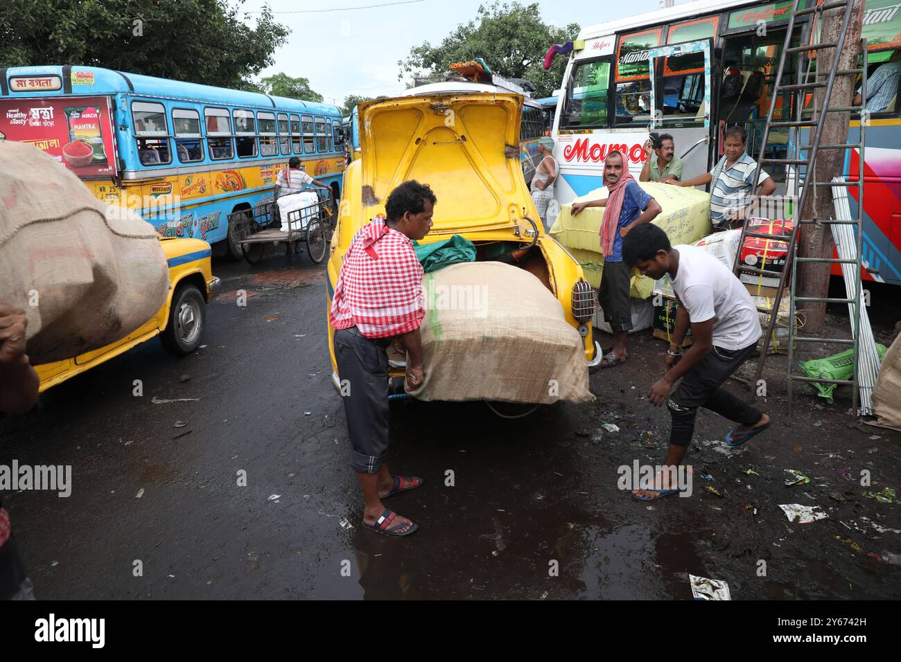 Kalkutta, Westbengalen, Indien. September 2024. Arbeiter entladen Konsumgüter aus einem gelben Ambassador-Taxiboot, um einen Bus zu laden, nachdem er am 24. September 2024 aus einem Nachbarstaat an einem Busbahnhof in Kalkutta, Indien, angekommen ist (Credit Image: © Rupak de Chowdhuri/ZUMA Press Wire). Nicht für kommerzielle ZWECKE! Stockfoto