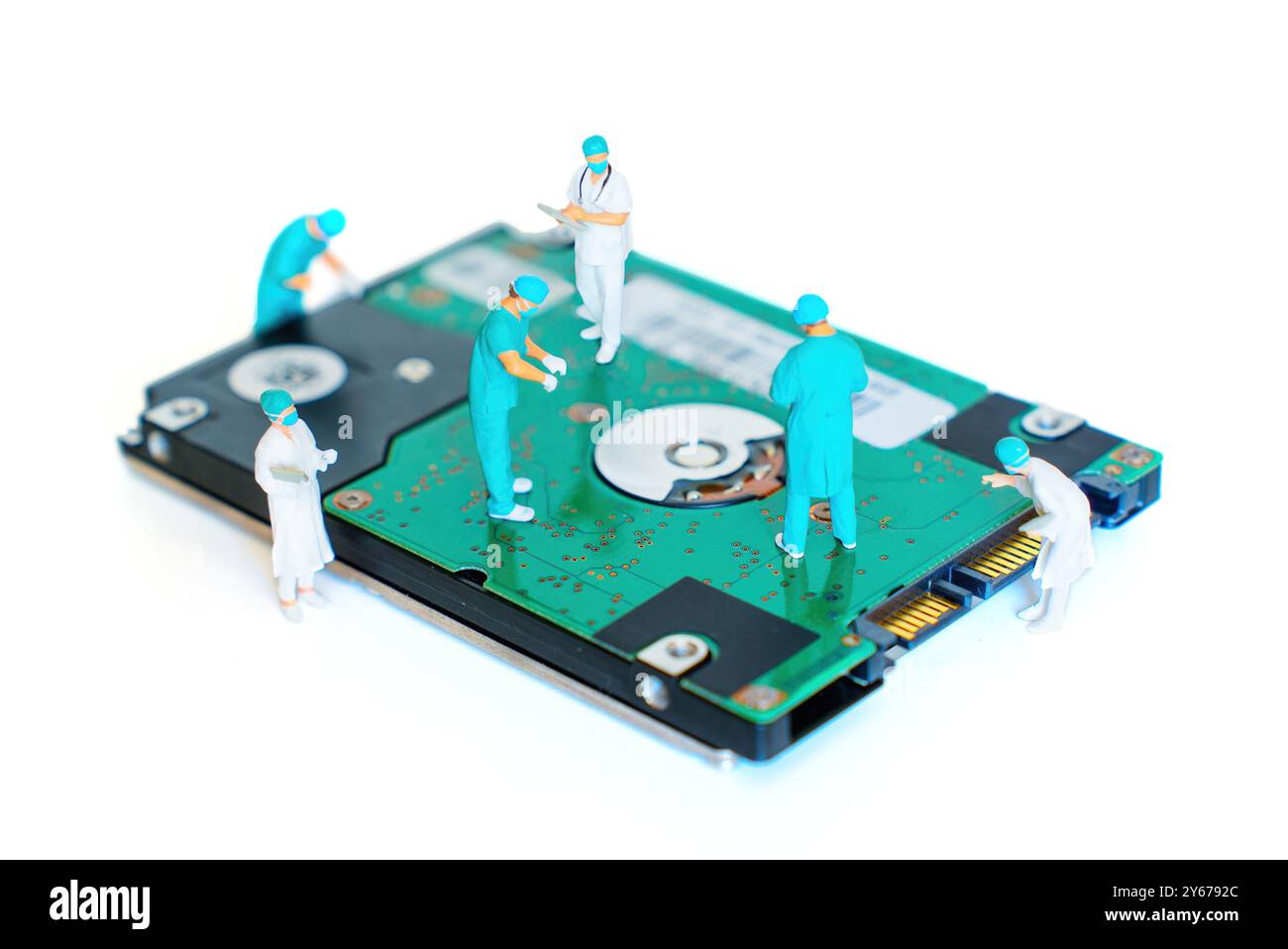 Miniaturfiguren von Chirurgen, die auf einer Festplatte arbeiten, symbolisieren Teamarbeit bei der Datenwiederherstellung und technischen Reparaturen. Stockfoto